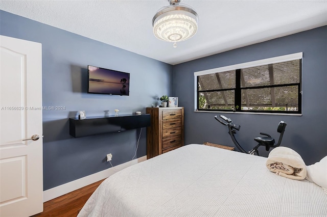 bedroom featuring a notable chandelier and dark hardwood / wood-style flooring