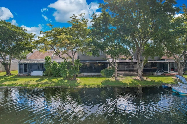 rear view of house featuring a water view, a yard, and a sunroom