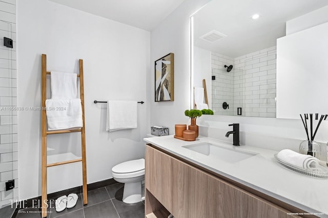 bathroom featuring tile patterned floors, toilet, a tile shower, and vanity