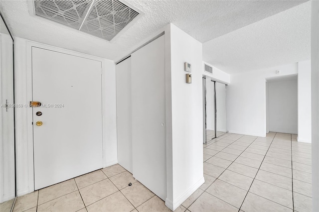 interior space featuring a textured ceiling and light tile patterned floors