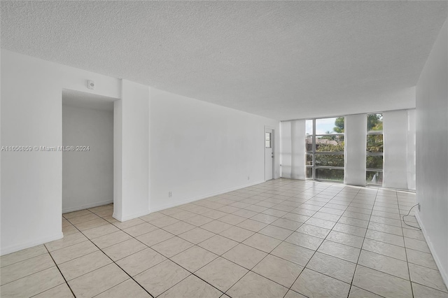 empty room with light tile patterned flooring and a textured ceiling