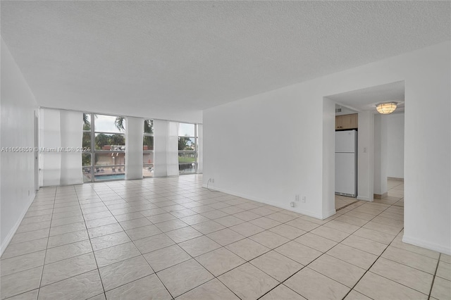 tiled spare room featuring a textured ceiling and a wall of windows