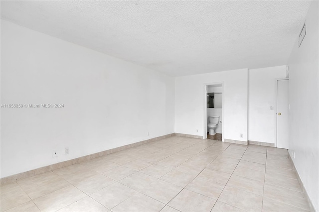 unfurnished room with a textured ceiling and light tile patterned floors