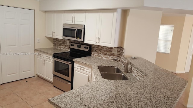 kitchen featuring kitchen peninsula, white cabinets, stainless steel appliances, and sink