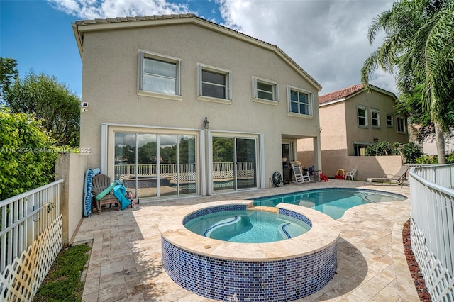 rear view of house with a swimming pool with hot tub and a patio