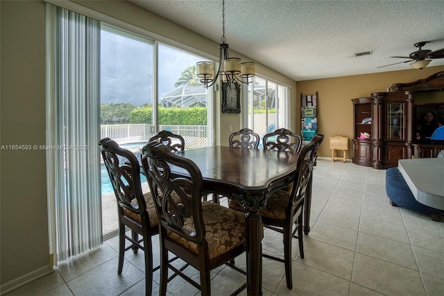 dining area with a textured ceiling, light tile patterned floors, and ceiling fan with notable chandelier