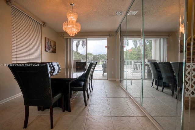 tiled dining space featuring a textured ceiling and a chandelier