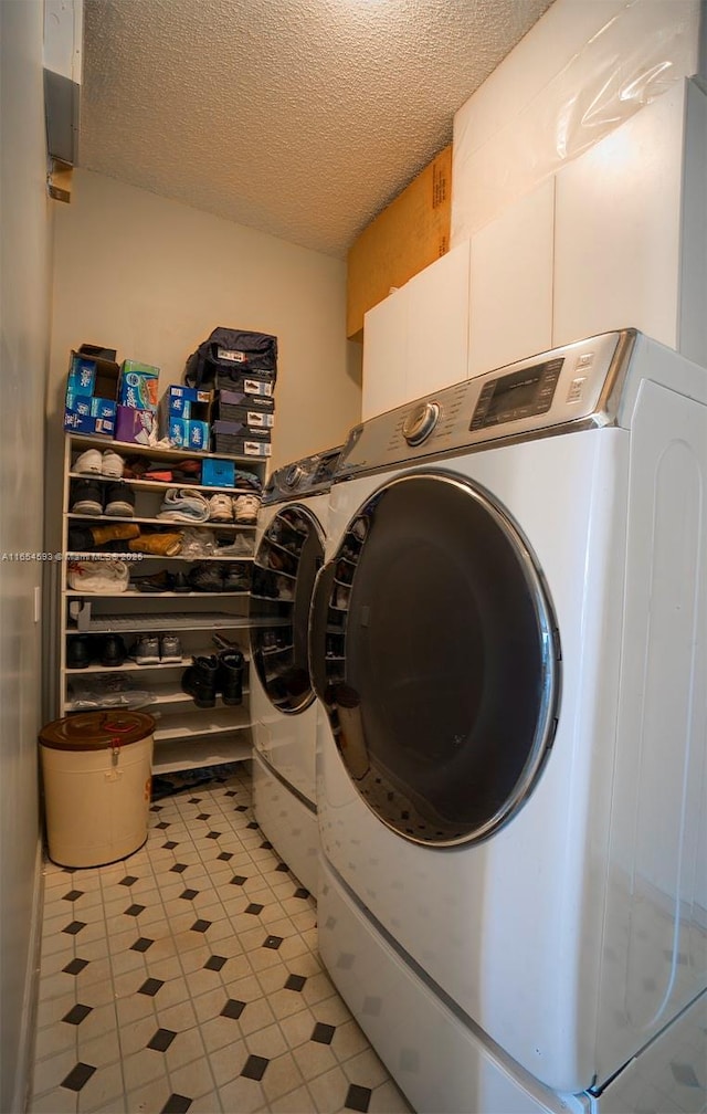 laundry room with a textured ceiling and washer and clothes dryer