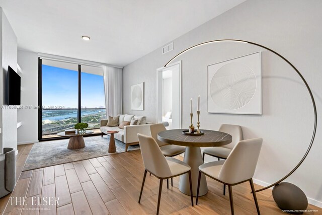 dining area with floor to ceiling windows and light hardwood / wood-style floors