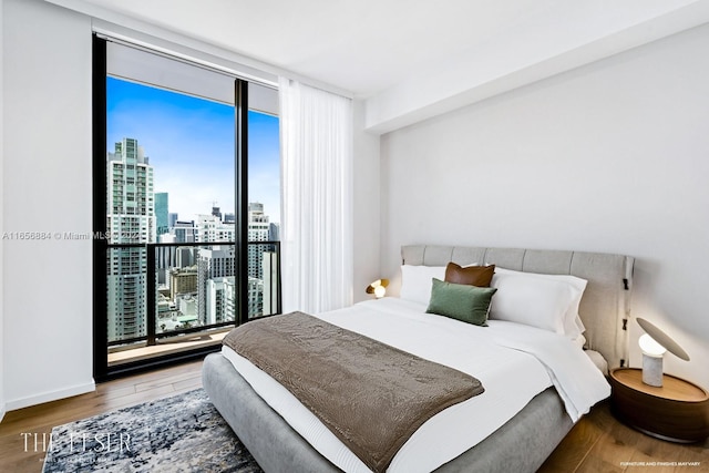 bedroom with wood-type flooring and expansive windows