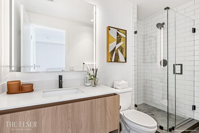 bathroom featuring vanity, toilet, and a shower with shower door