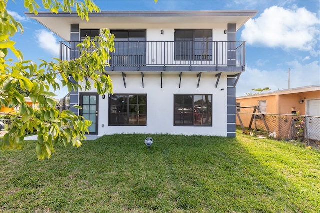 rear view of house featuring a lawn and a balcony