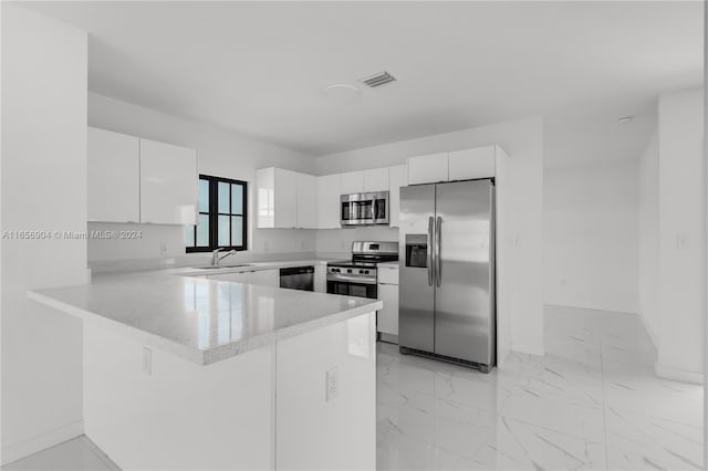 kitchen with kitchen peninsula, sink, white cabinets, and stainless steel appliances