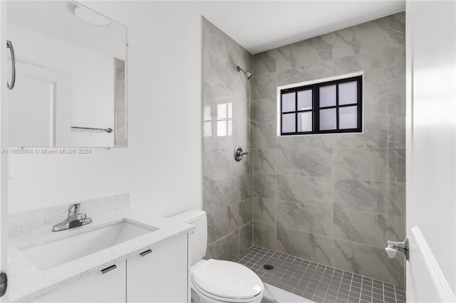 bathroom featuring a tile shower, vanity, and toilet