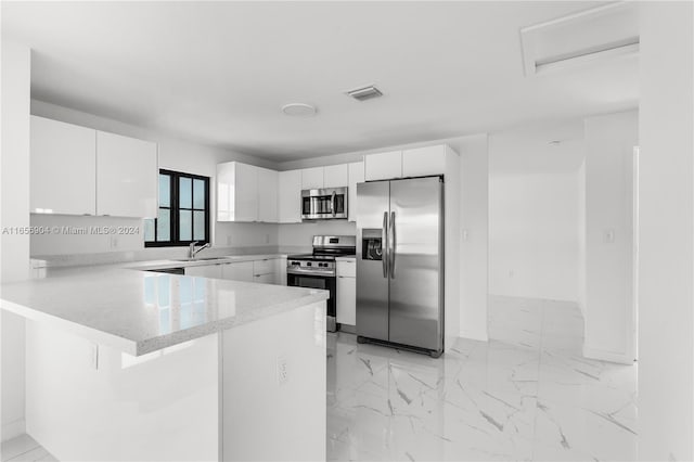 kitchen with kitchen peninsula, a kitchen breakfast bar, stainless steel appliances, sink, and white cabinets