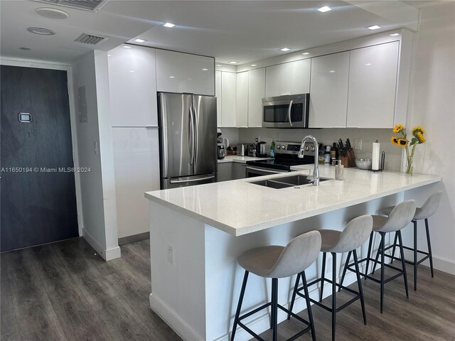 kitchen featuring stainless steel appliances, a kitchen breakfast bar, and white cabinets