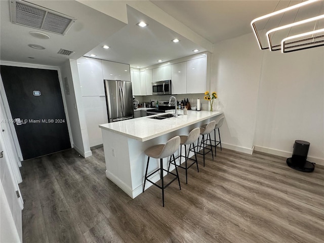 kitchen with white cabinetry, dark hardwood / wood-style flooring, a kitchen bar, and stainless steel appliances