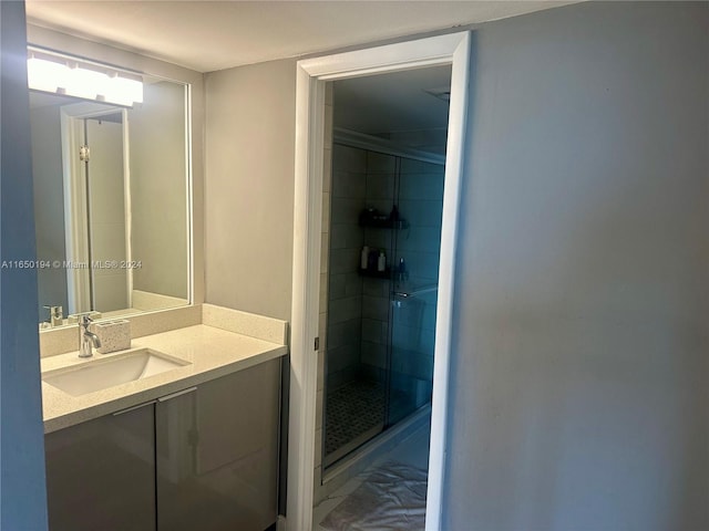 bathroom featuring a shower with door and vanity