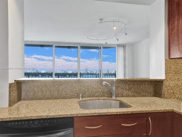 kitchen with dishwasher, sink, light stone countertops, and backsplash