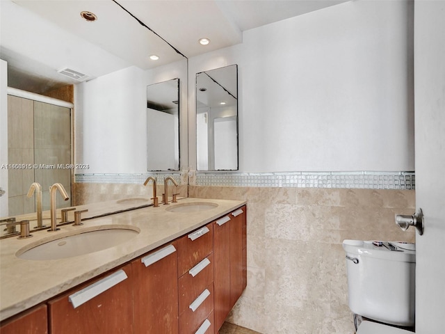 bathroom featuring tile walls, toilet, a shower with shower door, and vanity