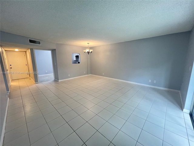 tiled empty room with an inviting chandelier and a textured ceiling