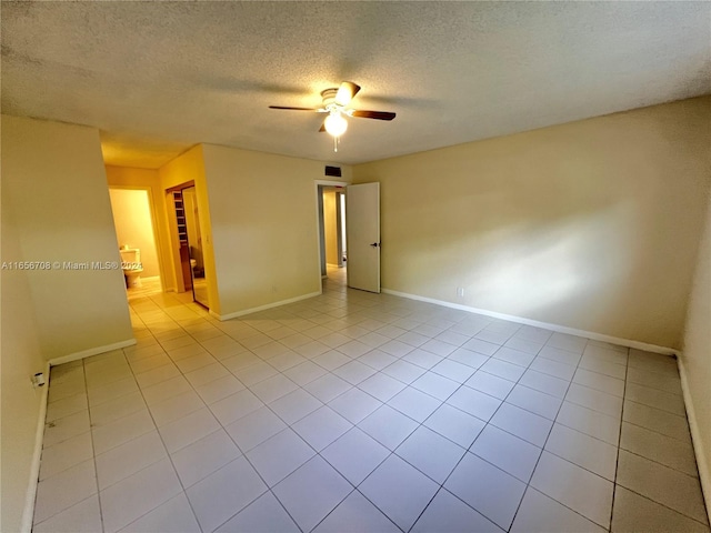 empty room with a textured ceiling, ceiling fan, and light tile patterned flooring