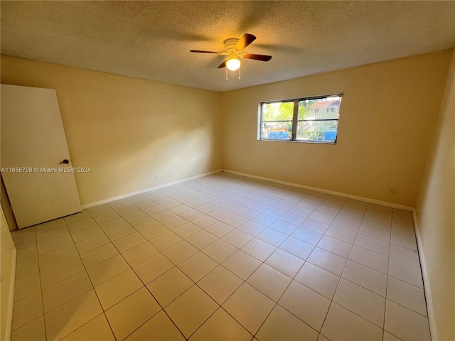 unfurnished room with ceiling fan, light tile patterned flooring, baseboards, and a textured ceiling