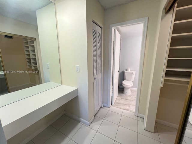 bathroom with tile patterned floors, toilet, and baseboards