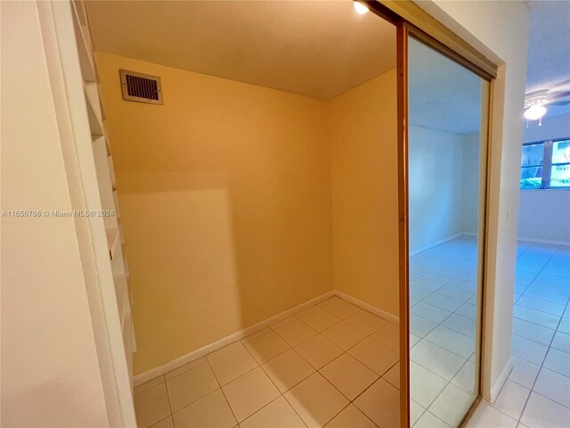 hallway with light tile patterned floors, baseboards, and visible vents