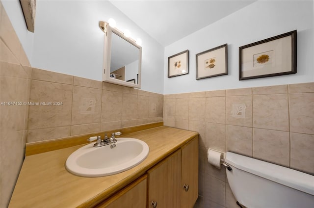 bathroom with vanity, tile walls, and toilet