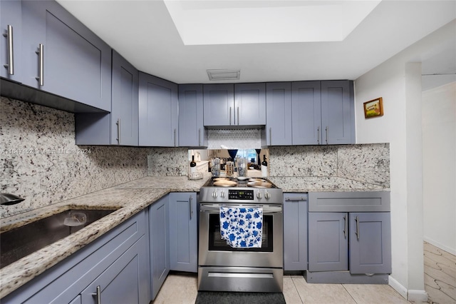 kitchen with light stone counters, electric range, sink, backsplash, and light tile patterned floors