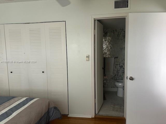 bedroom with a closet, hardwood / wood-style flooring, and connected bathroom