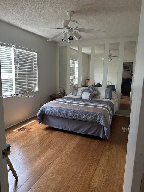 bedroom featuring ceiling fan, wood-type flooring, and a textured ceiling