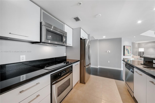 kitchen featuring appliances with stainless steel finishes, light tile patterned floors, and white cabinets