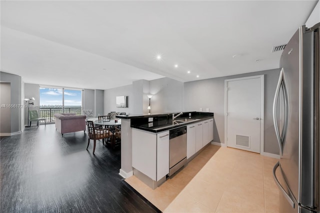 kitchen with sink, white cabinetry, stainless steel appliances, expansive windows, and kitchen peninsula