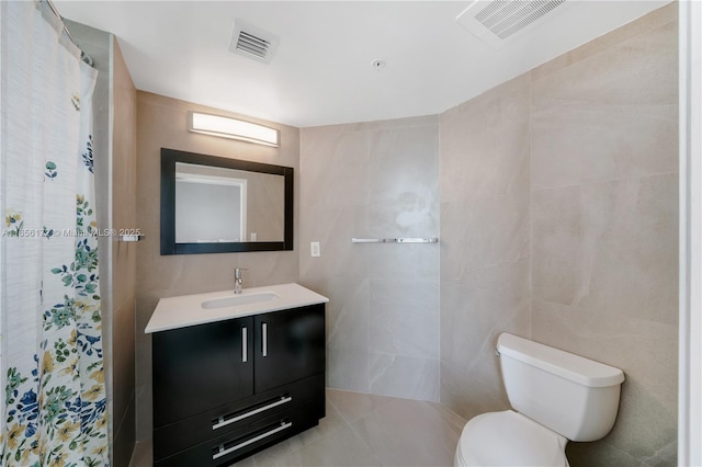 bathroom featuring tile walls, vanity, and toilet