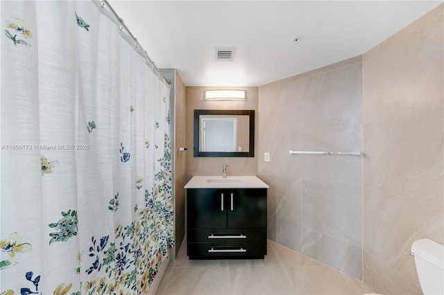 bathroom featuring a shower with curtain, vanity, tile walls, and toilet