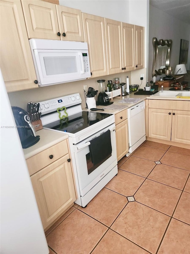 kitchen featuring light tile patterned floors, white appliances, light brown cabinetry, and sink