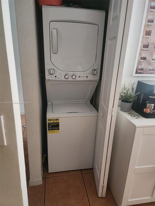 clothes washing area featuring light tile patterned flooring and stacked washer / drying machine