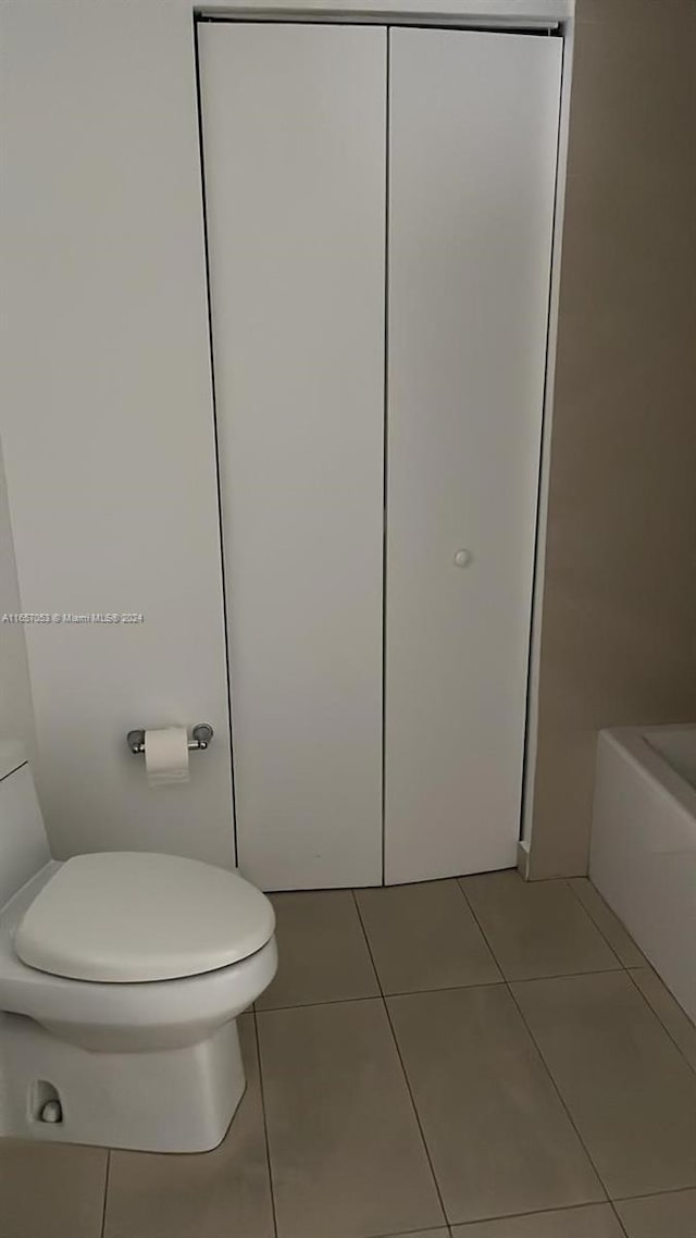 bathroom featuring toilet, a washtub, and tile patterned floors