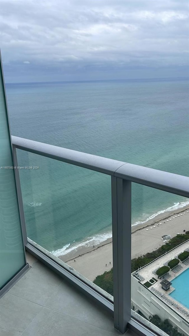 balcony featuring a view of the beach and a water view