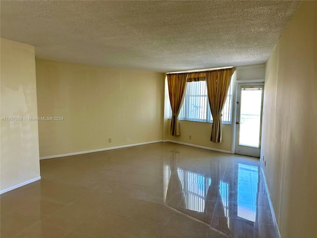 spare room featuring tile patterned flooring and a textured ceiling