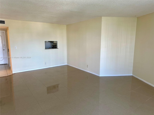 tiled spare room featuring a textured ceiling