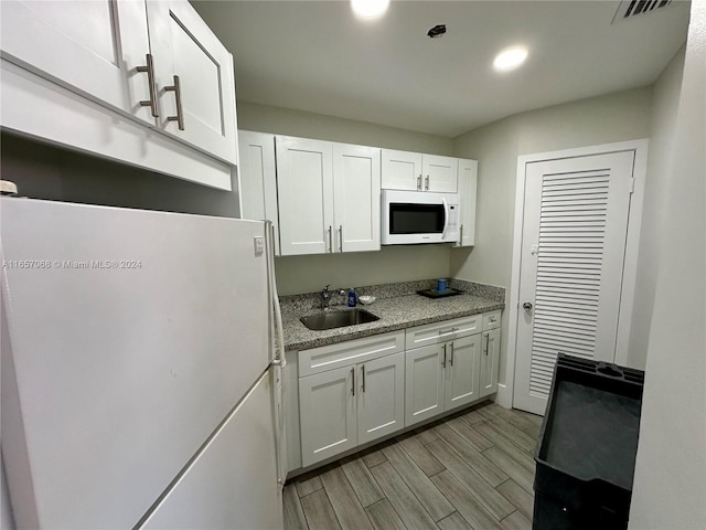 kitchen with light hardwood / wood-style floors, white cabinetry, white appliances, and sink