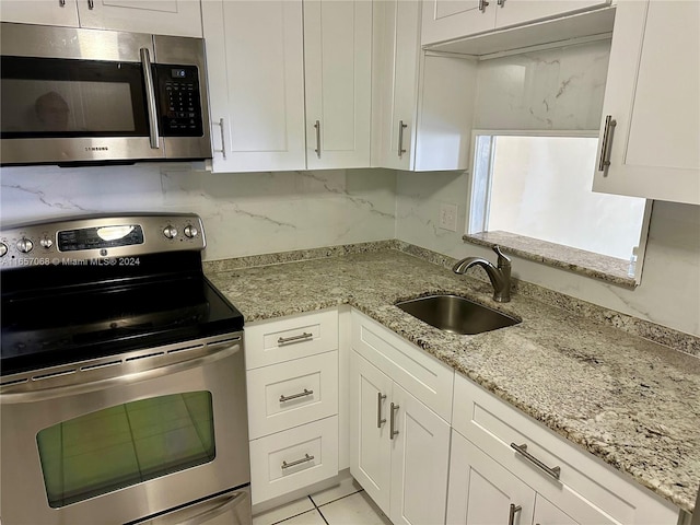 kitchen with white cabinets, appliances with stainless steel finishes, light stone counters, and sink