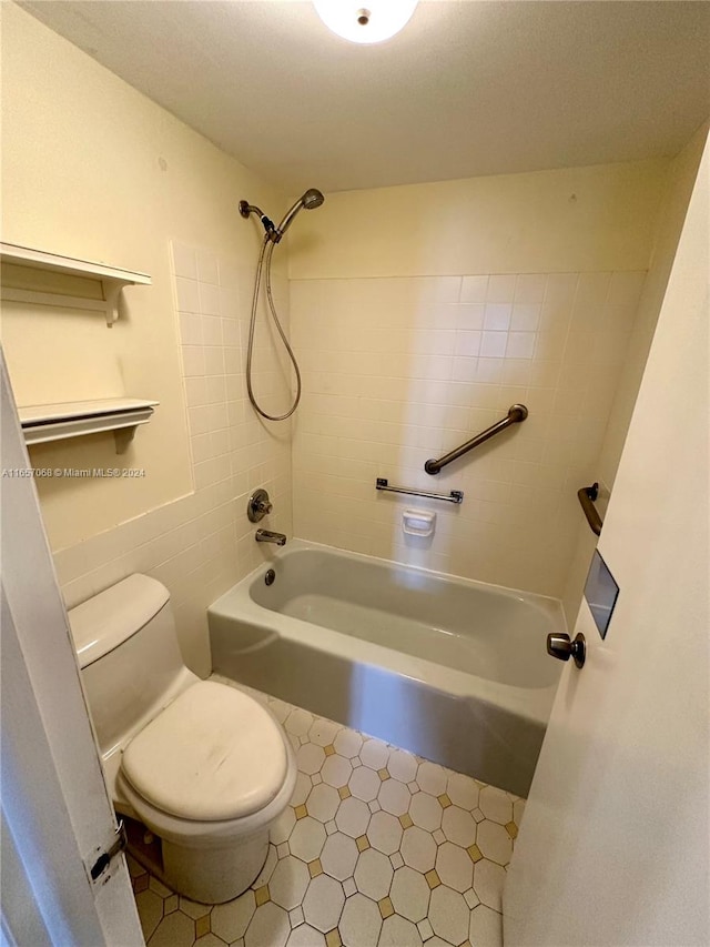 bathroom with tiled shower / bath combo and toilet