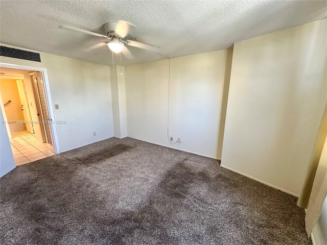 carpeted spare room with ceiling fan and a textured ceiling