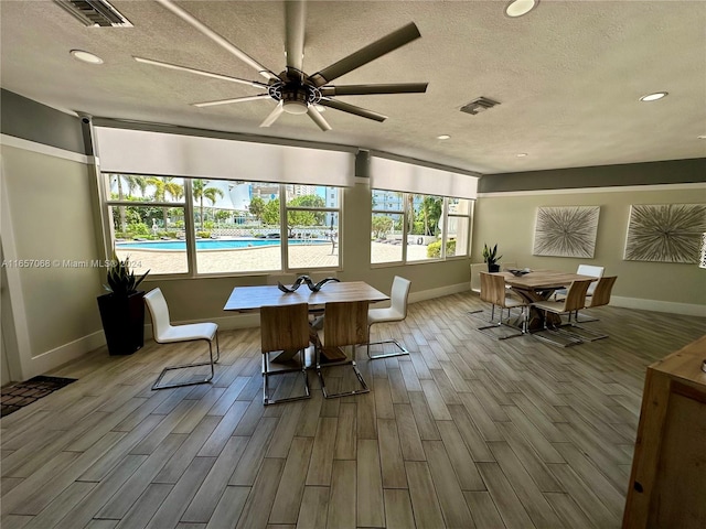 dining room with ceiling fan, a textured ceiling, and light hardwood / wood-style flooring