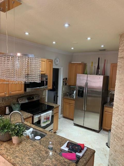 kitchen featuring light tile patterned flooring, sink, stone counters, stainless steel appliances, and backsplash