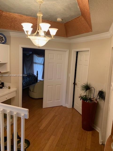 hallway featuring wood-type flooring, a chandelier, and crown molding